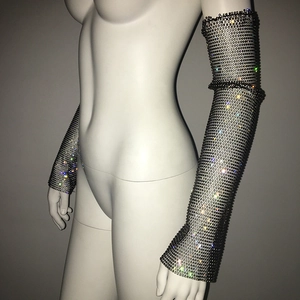 Detail of long fishnet arm sleeves with shimmering rhinestones on black mesh fabric