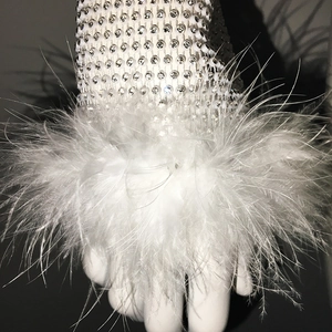 Detail of white mesh sleeve featuring sparkling rhinestones and elegant feather cuffs