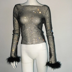 Detail of black mesh top with silver rhinestones and feather cuffs on a mannequin