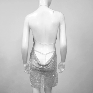 Detail eines silbernen Strass-Minikleids mit tiefem V-Rücken und Metallketten