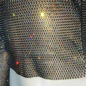 Macro detail of black fishnet mesh fabric with shimmering iridescent rhinestones