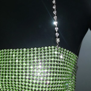 Detailed macro view of emerald green metal mesh fabric with sparkling purple rhinestones