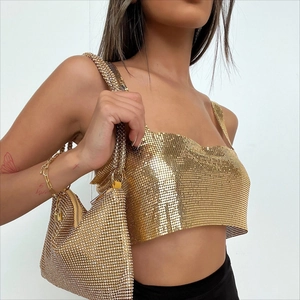 Detailed side view of a gold metal sequin crop top paired with a luxury rhinestone handbag