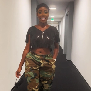 Dettaglio di un crop top nero con paillettes e scollo a V abbinato a pantaloni cargo mimetici