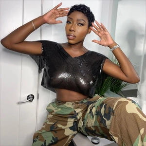 Dettaglio di un crop top nero con paillettes e scollo a V che mostra la trama a rete