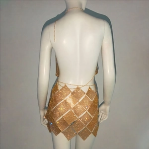 Détail d'une mini-robe en maille dorée avec dos nu et chaînes métalliques élégantes