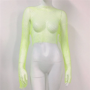 Detail of neon yellow mesh top featuring long sleeves and shimmering rhinestone accents