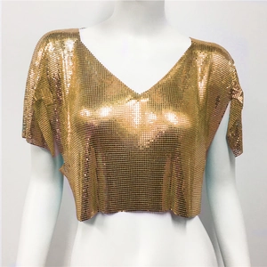 Dettaglio del tessuto a maglia metallica dorata con scollo a V sul top corto di paillettes