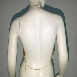Détail du haut dos nu doré montrant le design ouvert et la texture de chaîne en métal