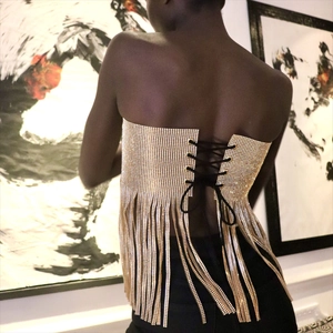 Détail d'un haut bustier doré à strass avec laçage noir au dos et longues franges