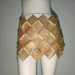 Détail d'une jupe en maille pailletée dorée avec des écailles métalliques en losange