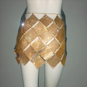 Détail d'une mini-jupe en maille de strass dorés avec chaînes métalliques et sequins