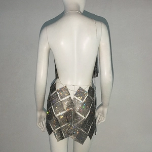 Détail du haut dos nu à paillettes et mini-jupe avec chaînes métalliques sur mannequin
