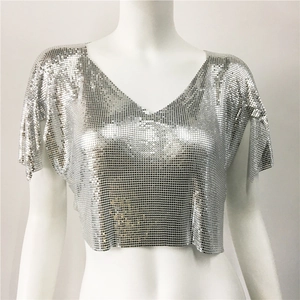 Dettaglio delle paillettes metalliche argentate scintillanti sul crop top con scollo a V