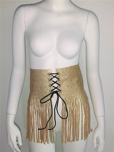 Détail d'un corset en maille métallique dorée avec laçage noir et longues franges de style