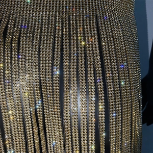 Dettaglio dell'abito con frange dorate e lussuose linee di cristalli di strass a doppia fila