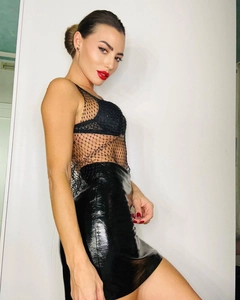 Detail of black mesh v-neck top with shimmering rhinestones and shiny leather skirt