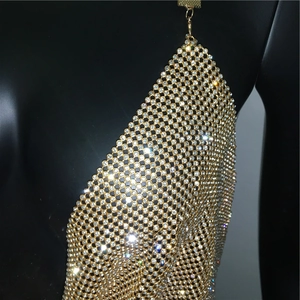 Dettaglio del top in maglia dorata con strass scintillanti su un manichino nero