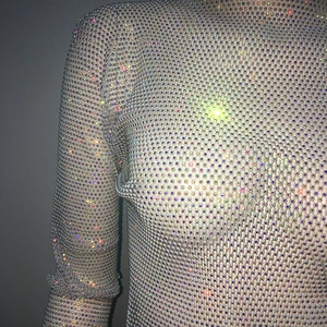 Detail of white mesh top featuring colorful rhinestones for stage or party wear