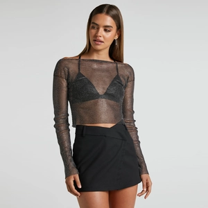 Dettaglio del crop top in rete nera con strass argentati e maniche lunghe scoperte sulle spalle