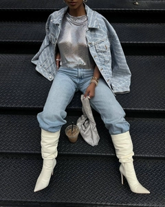 Gros plan sur un top à paillettes argentées avec une veste en jean et des bottes blanches