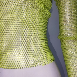 Detail of lime green mesh top featuring densely set white rhinestones and grid texture