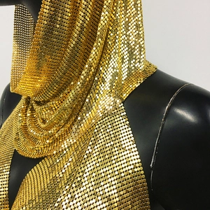 Détail du tissu à paillettes dorées montrant la texture métallique et le drapé luxueux