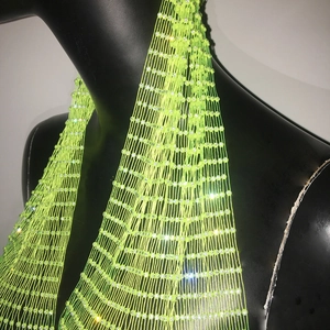 Détail du tissu en maille vert fluo avec strass blancs étincelants sur un haut de fête