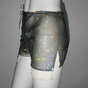 Detail of shimmering rhinestone fishnet shorts with side slits and drawstring waist