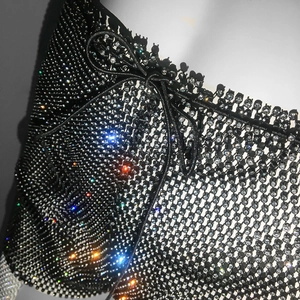 Detailed close-up of shiny rhinestones on black mesh fabric with drawstring bow tie