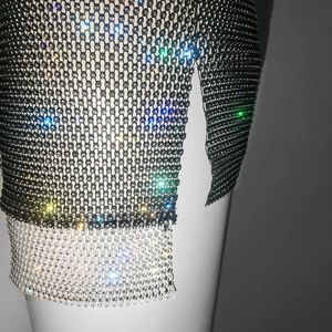Macro detail of rhinestone fishnet mesh fabric with side slit and black silver metal weave