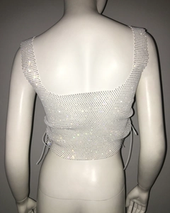 Detail of white rhinestone mesh crop top featuring side lace-up ties and sparkling gems