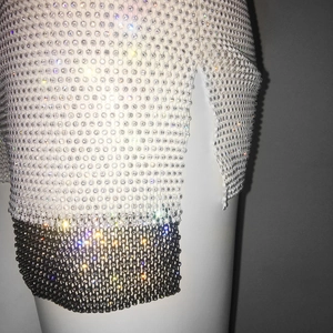 Detail of high waist mesh shorts featuring white and black rhinestones and side slit