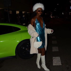 Detail of blue sequin mini dress paired with white faux fur coat and luxury saddle bag