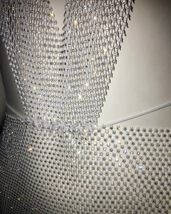Detailed close-up of sparkling silver rhinestone mesh fabric on a deep V-neck mini dress
