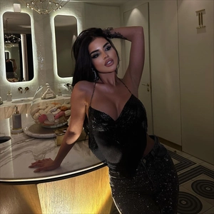 Détail du haut dos nu à paillettes noires avec chaînes métalliques et pantalon de soirée