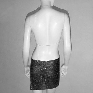 Détail de mini-jupe scintillante en strass avec une fine chaîne de corps en métal