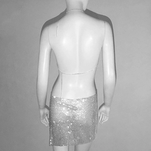 Détail du haut dos nu en strass avec chaînes métalliques et mini-jupe scintillante assortie
