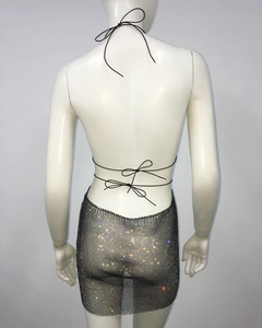 Close-up of sparkling rhinestone mesh dress featuring criss-cross back straps and tie detail
