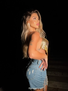 Détail du haut en maille métallique dorée et short en jean avec franges en strass argentés