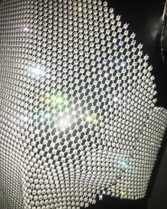 Gros plan sur des strass argentés et perles blanches sur un tissu résille noir chic