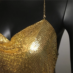 Close-up of golden metallic sequin mesh fabric with fine chain straps and reflective detail
