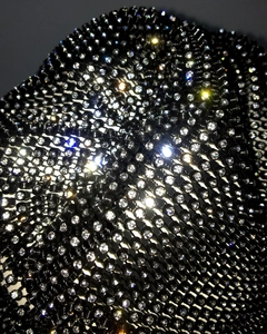 Detailed close-up of sparkling rhinestones on black mesh fabric for fashion accessory