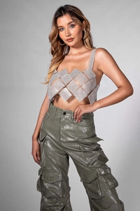 Detailed view of silver rhinestone geometric mesh top paired with green faux leather pants