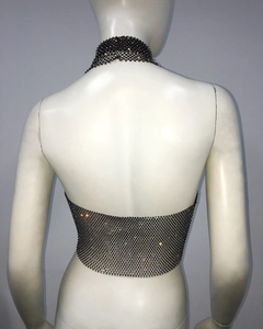 Détail d'un haut dos nu en résille noire orné de strass brillants et de chaînes en métal