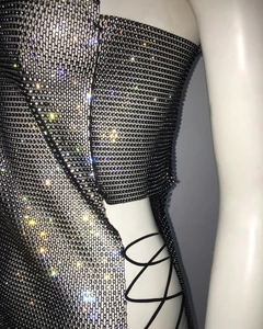 Détail d'une robe en résille noire ornée de strass brillants et laçage latéral sur mannequin