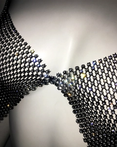 Close-up of sparkling rhinestones on black fishnet halter top with metallic texture