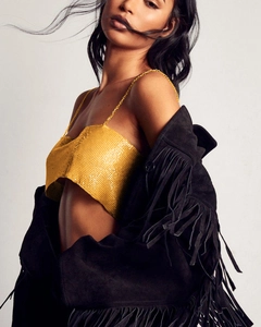 Détail du haut à paillettes dorées avec veste à franges noire pour un look de soirée