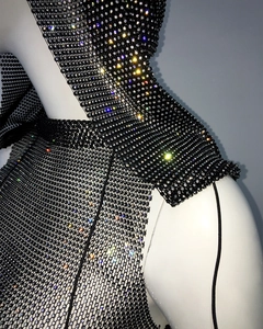 Dettaglio del top a rete nero con cappuccio e strass colorati scintillanti su un manichino