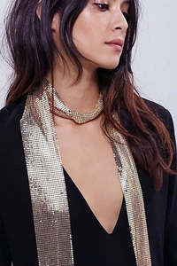 Detail of shimmering gold metal mesh scarf jewelry with elegant fluid texture drape